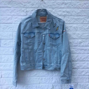  - En Levis jeansjacka med applikationer, jackan är typ i storlek L men passar mer som en S/M. Aldrig använd, prislapp finns kvar.