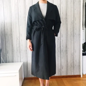  - Trenchcoat från Monki i mörkgrå. Passar till XS-S. Säljes för 150kr, frakt tillkommer. Betalning sker via swish