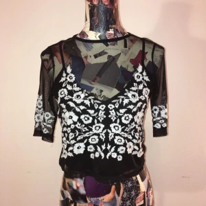  - Svart mesh topp med vita detaljer längs ärmar och framdel. Skön och snygg