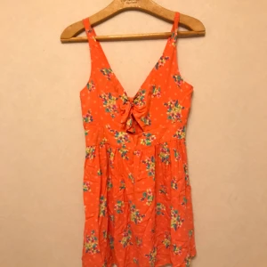  - Aprikos/Rosa sommarklänning med blommor från Hollister. Storlek S. Dragkedja i ryggen. Mjuk i tyget, 100% Viskos. Frakt tillkommer!