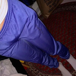 Kappa byxor  - Säljer mina fina lila byxor från Kappa! Älskar dem, riktigt fin färg men har tyvärr blivit för små:( har sytt in resårband vid ändarna men går enkelt att klippa bort om man inte vill ha dem tighta där nere! Går att knyta vid midjan. Jättebra skick