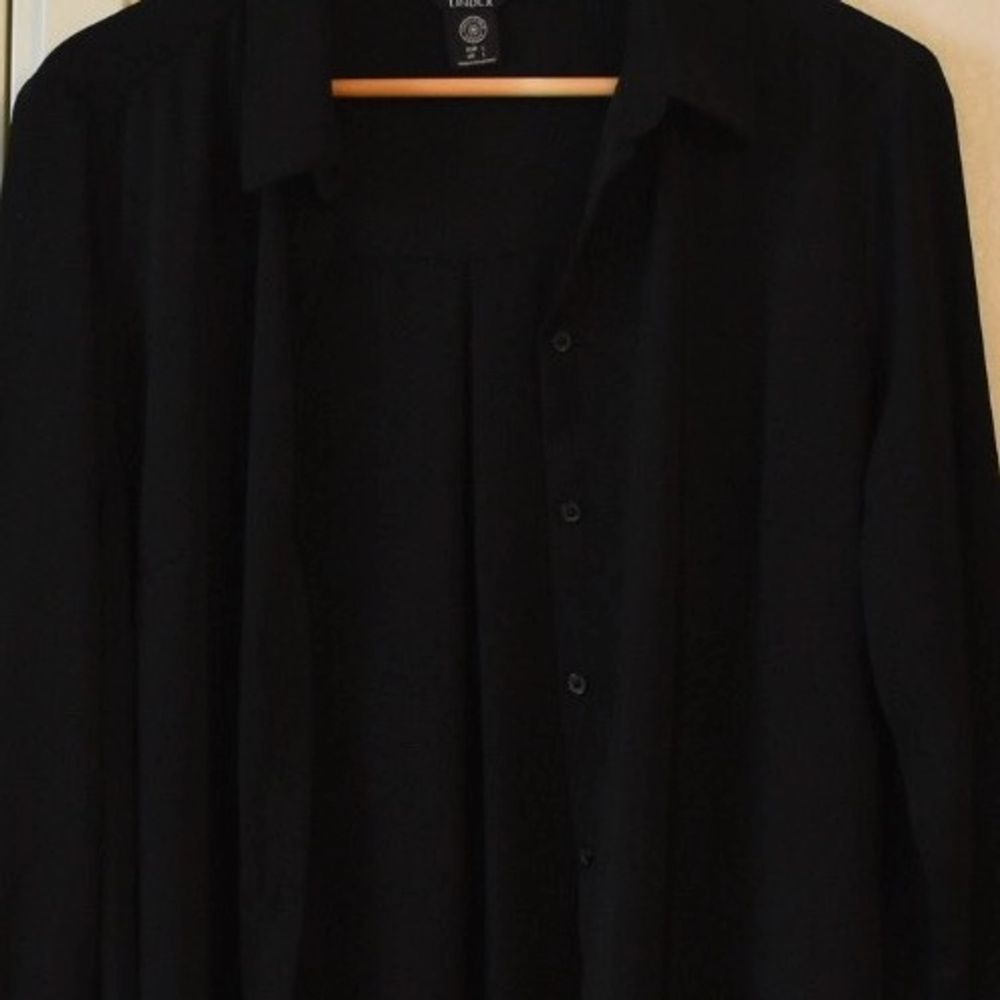 En lång svart jättefin skjorta som kan användas både till vardags och till finare tillställningar. Skulle kunna passa M-L. Den är från Lindex.  Nypris var kring 300-400 kr om jag minns rätt. Inte använd många gånger, den är i fint skick.. Skjortor.