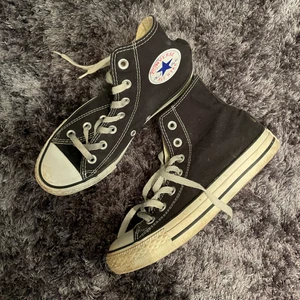 Svarta converse - Trendiga svarta höga converse i storlek 37. Köpta för ett tag sen men knappt använda, har bara stått i en skohylla. Tyvärr är dom för små för mig så måste sälja. Lite smått dammiga då det bara stått, men inga fläckar eller så, tyvärr är själva converse märket lite skadat (se första bilden) men verkligen inget man tänker på. 