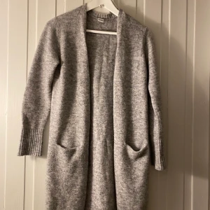 Grå kofta - Grå lång trendig kofta. Denna är egentligen köpt på barnavdelningen men passar bra till någon med storlek S eller XS.