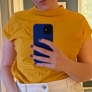 T-shirt från WEEKDAY - Senapsgul t-shirt från Weekday. Storlek S men OS så passar mig som i vanliga fall är en stor L. Använd 2 ggr men kommer inte riktigt överens med färgen, annars är det BÄSTA modellen av T-shirt 🤤 katt finns i hemmet och frakt tillkommer. 