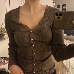 Figurformad topp - Säljer denna figurformade toppen! Sitter super snyggt på, i nyansen brun, med spets vid handlederna och hela knäppningen❤️Man kan även knäppa upp hela och ha den som en tunn kofta. Köparen står för frakten! Nu ligger den på 180kr