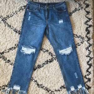 Helt oanvända jeans från Missguided! Håliga med fransar nedtill, mellanblå jeansfärg. Passar bra över lår och höfter på någon som normalt är en medium/26-27a i jeans.