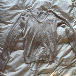  - Beige mjuk V-ringad långärmad. Mjukt material. Använd få gånger. Fin dekoration vid ärmarna. 