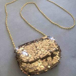 Liten väska (ca 10x13 cm) med guldpaljetter och guldfärgad kedja. ✨🎉 Oanvänd.  Frakt tillkommer.
