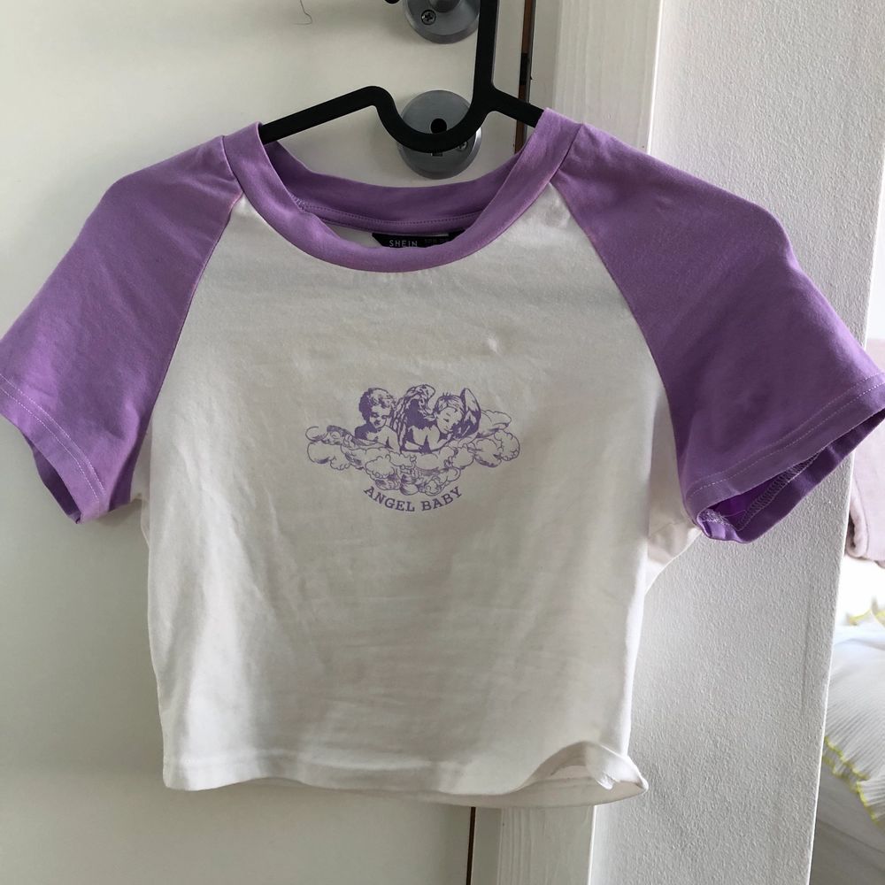 Jättesöt croppad t-shirt med lila änglatryck från shein. Säljer då den knappt kommer till användning. Inga fläckar eller skador. Frakt tillkommer❣️. Toppar.
