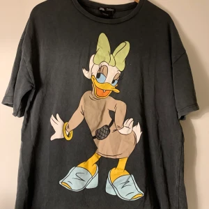 Stentvättad T-shirt med Disney motiv - Skitsnygg grå stentvättad lite over-sized T-shirt med Kajsa Anka! Zara X Disney. T-shirt i gott skick!!🦄🦄🦄