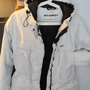 Vit vinterjacka  - Jackan är i ett bra skick,  väldigt lite använd.    Jackan är en lång modell utan päls