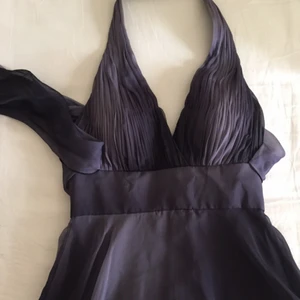  - Långklänning som skiftar i grå/blått. Halterneck, samt med knytning bak. Tillhörande sjal medföljer. Ingen storlekslapp kvar men passar en 36:a. Använd två ggr, gott skick.  Jag bjuder på frakten. 