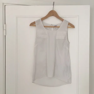  - Skir vacker top/blus med hög ringning. Passar perfekt till ett par svarta stuprörsjeans och en öppen kofta. Något längre där bak. Perfekt till våren och sommaren! 