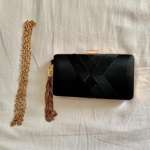 Svart/guld clutch väska - Endast använd vid ett tillfälle, tillhörande kedja ingår (med kedjan på blir det en axelremsväska) 