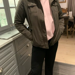 Svea jacka  - Svea jacka i mörkgrön med lurvig luva