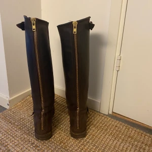 Primeboots - Höga primeboots i brun färg med guldiga detaljer. Några år gamla men sparsamt använda