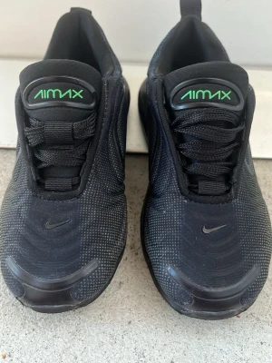 Nike Air Max svarta sneakers - Säljer ett par svarta Nike Air Max sneakers med gröna detaljer och tydlig Air Max-logga på plösen. Skorna har en sportig siluett, synlig Air-sula och är gjorda i textil och syntet. Swoosh-logga finns både på sidan och framtill. Perfekta för dig som gillar streetwear och snygg design.