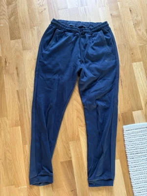 Mörkblå mjukisbyxor från BOSS - Säljer ett par mörkblå mjukisbyxor från BOSS med broderad logga på vänster ficka. Storlek S.