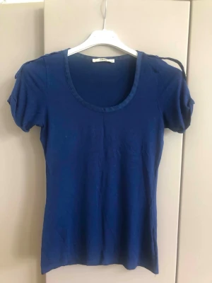 Blå t-shirt med rund hals från Oasis - En enkel och stilren blå t-shirt från Oasis med rundad halsringning och korta ärmar. T-shirten har en smal passform och är tillverkad i mjuk bomull, perfekt för en avslappnad look. Armhåla till armhåla 38 cm