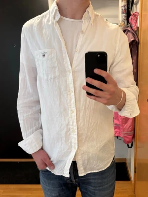 Vit linneskjorta från Gant - Klassisk vit skjorta från Gant i svalt linne. Skjortan har lång ärm, bröstficka med Morris-logga och knappar hela vägen. Pris går att diskutera!