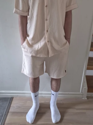 Beige set från Polo Ralph Lauren - Säljer ett par beige ribbade shorts med Polo Ralph Lauren. De har en relaxed passform, elastisk midja och diskret logga broderad på benet. Perfekta för chill dagar och matchar snyggt med en overshirt eller t-shirt.