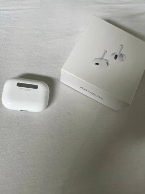 Apple AirPods Pro 2nd Gen - Säljer ett par vita Apple AirPods Pro (andra generationen) med laddningsetui och originalförpackning. Snygg och kompakt design i blankt plastmaterial. Perfekta för trådlös musik och samtal med grymt ljud och brusreducering.
