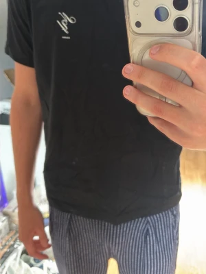 Svart t-shirt från Suxxess - Svart t-shirt från HM med vit logga på bröstet och stor grafisk print på ryggen. 