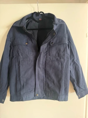 Blå overshirt med fickor och dragkedja - Snygg blå overshirt med lång ärm och två bröstfickor. Jackan har dragkedja framtill med tryckknappar och en avslappnad passform. Perfekt att slänga över en hoodie eller t-shirt för en casual look.