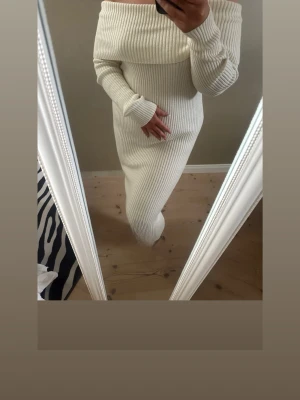 Vit ribbad offshoulder långklänning - Säljer en superfin vit ribbad långklänning med offshoulder och långa ärmar. Klänningen är stickad och har en figurnära passform som framhäver siluetten. Perfekt för dig som vill ha en stilren och trendig look.