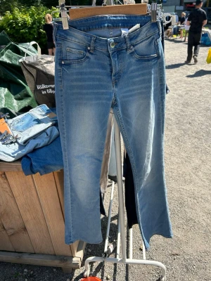 Bootcut jeans från &Denim ljusblå - Säljer ett par ljusblå bootcut jeans från &Denim med låg midja. Jeansen har klassiska fem fickor, snygga slitningar och en avslappnad passform nertill. Perfekta för dig som gillar en retro vibe och vill ha ett par jeans som sticker ut.