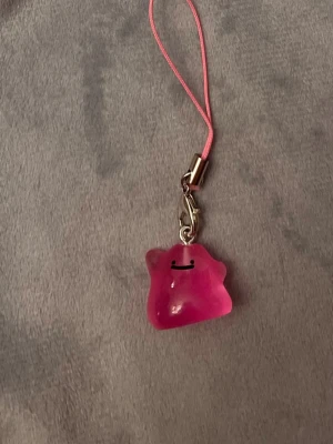 Ditto Mobilsmycke Pokemon hänge Ditto Nyckelring Pokemon - Jättegulligt hänge med en rosa Ditto! Den är dessutom självlysande och lyser i mörkret.   Ditto-berlocken är ca 1,5 x 1,5 centimeter. Öglan är ca 5 cm lång.  Jättefin att sätta på din mobil, väskan, ditt 3DS, Switch eller i nycklarna exempelvis! 