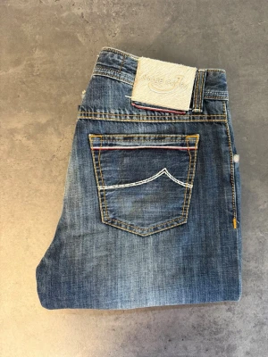 Blå jeans Jacob Cohen 688 Limited Edition 097 of 210 W32 - Snygga blå jeans från Jacob Cohen med raka ben och klassisk femficksmodell. Jeansen har kontrastsömmar i vitt och gult samt en unik detalj med färgad söm på bakfickan. Tillverkade i slitstark denim, perfekta för en avslappnad stil.
