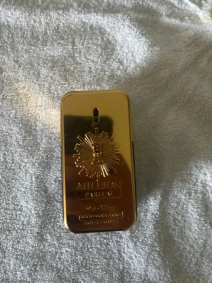 Paco Rabanne 1 Million Parfum 50ml - Snygg parfymflaska i guld från Paco Rabanne, modellen 1 Million Parfum. Flaskan har en rektangulär form med metallisk guldfinish och tydliga detaljer på framsidan. Parfymen är bärnstensfärgad och flaskan känns lyxig och modern. Ca hälften kvar därav priset.