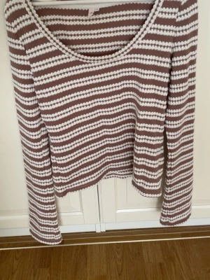 Randig brun och vit långärmad topp - Säljer en brun och vit randig långärmad topp från NELLY. Toppen har rund halsringning och är gjord i ett mjukt, ribbat material som sitter bekvämt. Perfekt till jeans eller kjol för en chill look. Helt ny!! 
