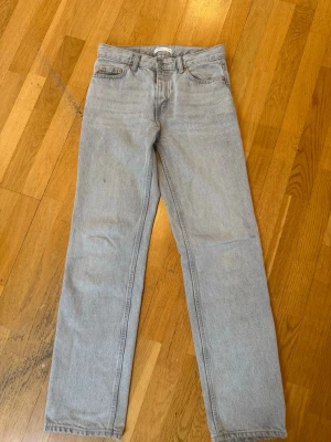 Ljusgrå raka jeans - Säljer ett par ljusgrå jeans med rak passform och medellåg midja. Jeansen är från gina tricot och jag säljer dessa då de blivit för små. På bild 3 ser man att det är två små hål på insidan av midjan, detta för att när jag köpte dessa så var de för små och jag satte skosnöre genom midjan, men det är inget som syns på utsidan. 