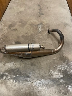 Avgassystem till moped, Tecnigas - Säljer ett avgassystem från Tecnigas till moped. Utsvängd form med ljuddämpare i silverfärgat metallmaterial. Passar till tvåtaktsmotorer och ger sportigare ljud och prestanda. Perfekt för dig som vill uppgradera mopeden.