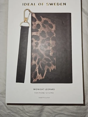 iDeal of Sweden Midnight Leopard skal - Snyggt fodral till iphone 12/12 pro skall med leopardmönster i svart och brunt från iDeal Of Sweden med avtagbar handledsrem. Tillverkat i konstläder med gulddetaljer för en trendig look. Skalet följer ej med