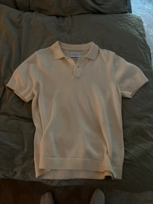 Beige linnetopp med krage från Vailent - Snygg beige linnetopp från Vailent med klassisk krage och korta ärmar. Toppen har en stickad känsla och knäppning framtill. Perfekt för en chill och stilren look. Använd fåtal gånger.