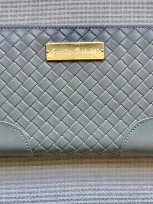 Oanvänd ljusgrå Carla Belotti plånbok i läder - Elegant rymlig plånbok (21×11 cm) från Carla Belotti i ljusgrått läder med flätat mönster och gulddetaljer. Aldrig använd, men har fått några mindre märken/tryckskador på utsidan av att ha legat förvarad (se bilder noga). Insidan är i nyskick! Dragkedja runt om, massor av kortfack, sedelfack och ett separat myntfack med dragkedja. Perfekt för dig som vill ha en organiserad och lyxig plånbok! Skickas snabbt. Skriv vid frågor ✨