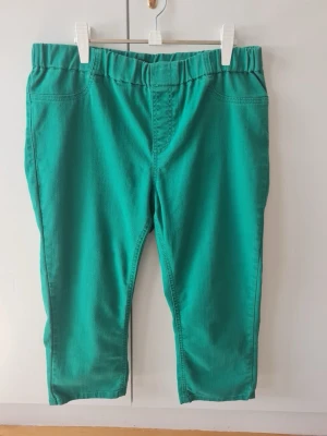 Capri byxor från KappAhl strl 46 (dam) - Snygga gröna Capri byxor från KappAhl med elastisk midja för extra komfort. Byxorna har en enkel design med två bakfickor. Passar bra till både vardag och mer avslappnade tillfällen.   Storlek 46.