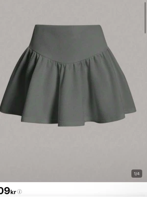 Mörkgrå vid kjol med hög midja - Supersnygg mörkgrå kjol med hög midja och utsvängd, voluminös form. Kjolen har en enkel men trendig design och är tillverkad i ett mjukt, lite tjockare tyg som ger ett fint fall. Perfekt för dig som gillar en stilren och modern look.