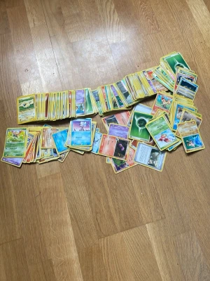Pokémon kort - 450-500 st Pokémon kort! Ingen aning vad dem kan kosta idag, så ge pris förslag. Perfekt present för dig som vill köpa till ditt barn eller liknande. Korten är väldigt gamla, vilket betyder att dem kostar mycket mer än vad dem gjorde förut. Kolla bilderna för att se vad AI skrev. 