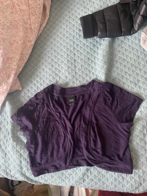 Lila bolerotopp från Esprit - Kort lila bolerotopp från Esprit med öppen front och korta ärmar. Endast använd 1 gång. Den är i storlek M men sitter som S