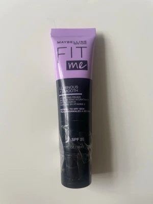 Maybelline Fit Me Luminous + Smooth Primer - Primer från Maybelline Fit Me-serien i en lila och svart tub. Ger en återfuktande och lystergivande bas med SPF 20, perfekt för normal till torr hud. Innehåller vitamin E och ger en jämn och fräsch finish. Aldrig öppnad.