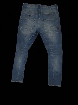 Blå slim fit jeans med slitningar - Snygga blå slim fit jeans med lätt slitna detaljer på låren och klassiska fem fickor. Jeansen har en modern passform och är tillverkade i denim med stretch för extra komfort. Perfekta för en avslappnad och trendig look.