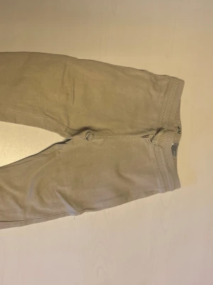 Beige leggings från H&M - Snygga beige mjukisbyxor från H&M med bred resår i midjan. De är tillverkade i ett mjukt material som sitter skönt på kroppen. Perfekta att matcha med oversized tröjor eller hoodies.
