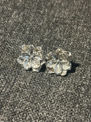 Silvriga blomformade örhängen - Snygga silvriga örhängen i form av blommor med detaljerade blad. De är gjorda i metall och har en cool, glansig finish. Perfekta för dig som gillar unika accessoarer med naturinspirerad design. Endast testade 