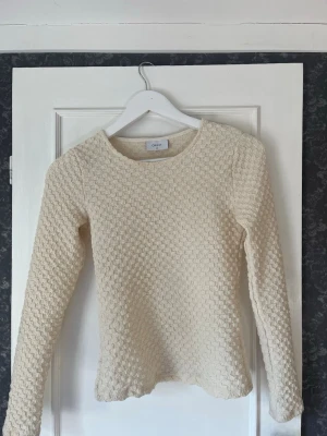 Beige stickad tröja från Grunt - Säljer en beige långärmad tröja från Grunt köpt på jeansbolaget. Med ett snyggt strukturerat mönster. I storlek XS/XXS ungefär. Storleken är M i barnstorlek. Tröjan har rund halsringning som ger en cool och modern look. Perfekt att styla med jeans eller kjol. Nypris ca 300kr❣️