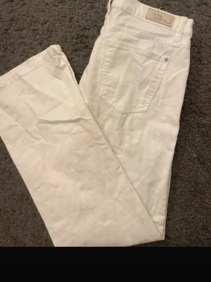 Vita bootcut jeans från LTB - Snygga vita jeans från LTB med bootcut-passform och klassiska fem fickor. Jeansen har normal midja och är tillverkade i ett mjukt bomullsmaterial med lite stretch för extra komfort. Perfekta för dig som vill ha en fräsch och stilren look. Midjemått: 38,5cm Innerbenslängd: 76cm 
